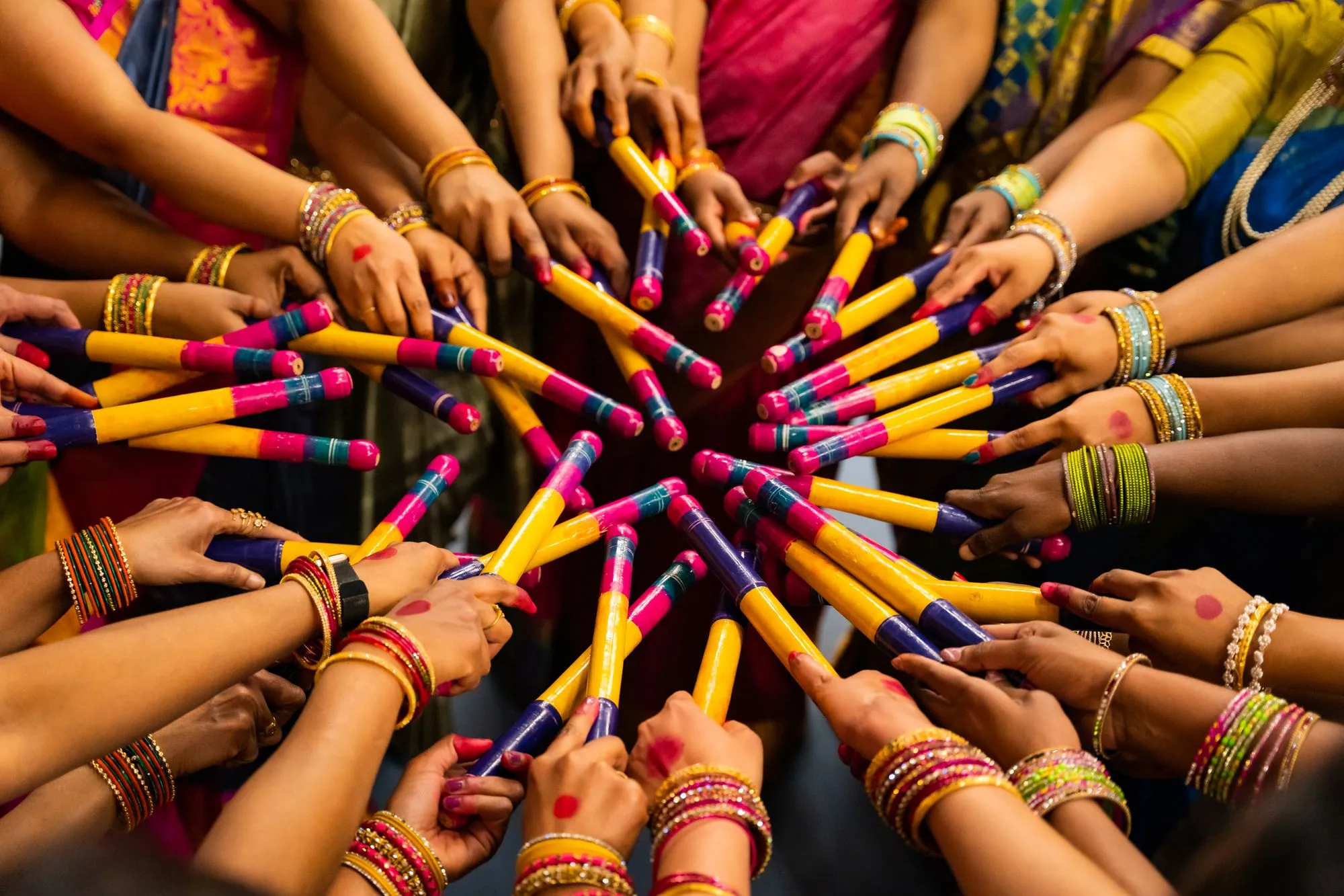 Hands holding dandiya sticks together in a circle at a Navratri celebration