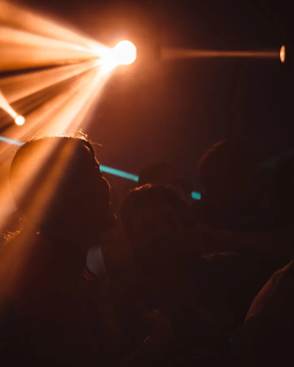 Silhouetted crowd under warm beams of club light