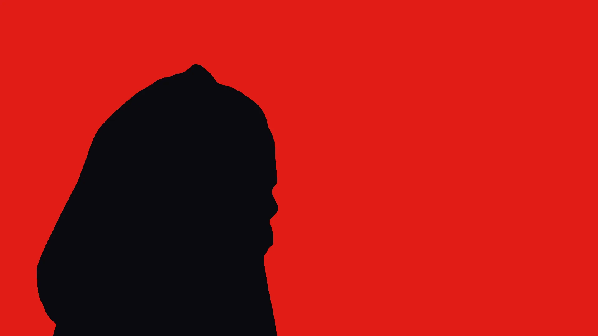 A figure in a hood, silhouetted against red stage light