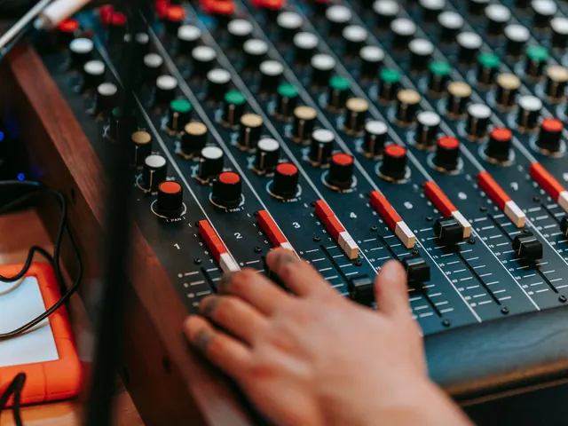 A hand adjusting a sound mixing console